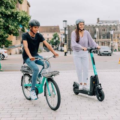 Image of young man on a bike and young woman on a scooter