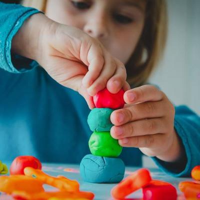 Photograph of child placing different coloured playdough blobs on top of each other