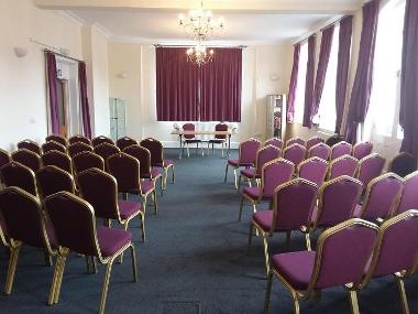 Photo of Assembly Room Downham Market showing chairs in rows, carpeted floor and a chandelier