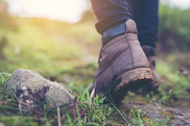 Close-up photograph of the walking boots of someone walking on grass