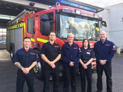 5 firefighters stood in front of a fire engine