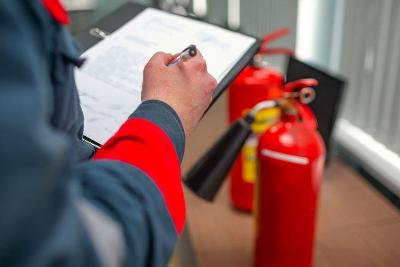 Person in firefighter uniform filling in a fire inspection form on a clipboard