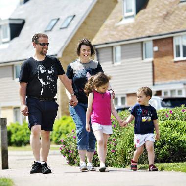 Two parents and two children walking together in a residential area