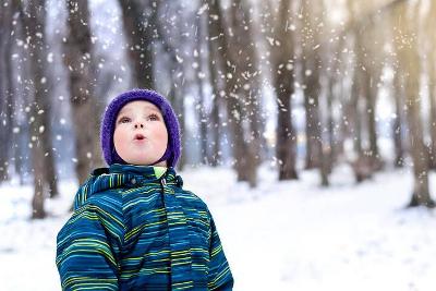 A boy looking up at snowfall while standing in a wintry field