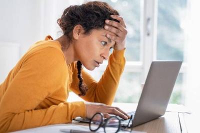 Woman looking at laptop screen with concerned expression 