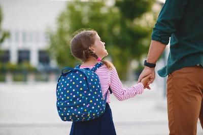 A father holding hands with his daughter as he walks her to school