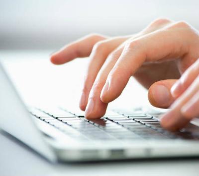 A person's hands typing on a laptop keyboard 