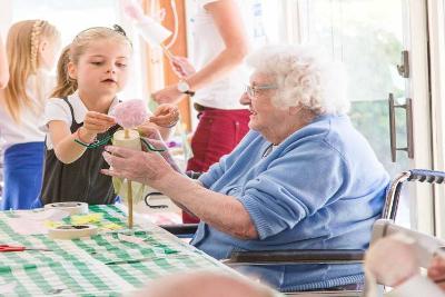 Child and older person working together to decorate a puppet 