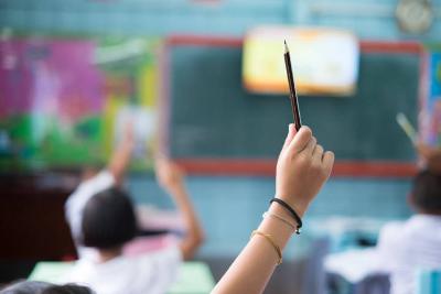 Child raising their hand in a classroom