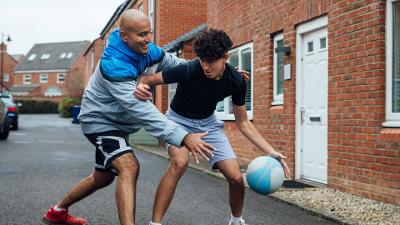 Man and teenage boy playing basketball