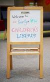 Whiteboard sign that reads ‘Welcome to our lovely and new Children’s Library’ 