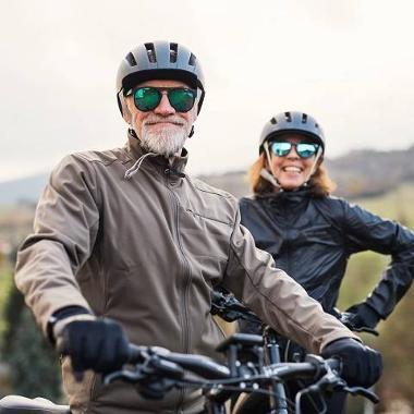 Two people on bikes with helmets and sunglasses 