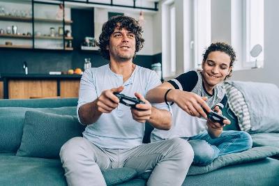 Man and teenage boy on sofa playing video games 720 x 480