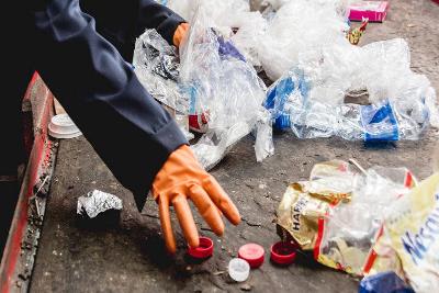 Person wearing gloves picking up plastic waste 