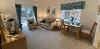 Photograph of Meadow Walk sitting area with items such as sofa, armchair, dining table for two, double-doors onto garden.