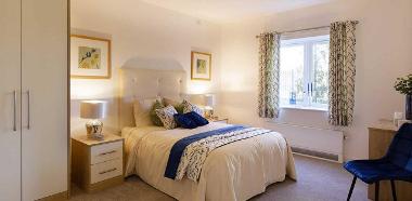 Photograph of a double bedroom at Meadow Walk including bedside tables, wardrobe, small table and chair.