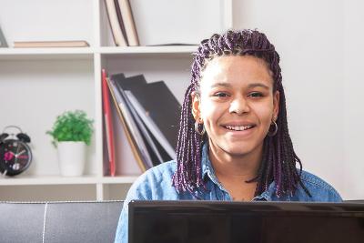 A woman smiling and looking at the camera over a laptop screen