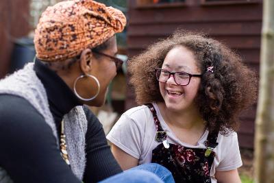 Female adult and teenage girl smiling at each other