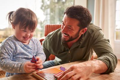 Dad sitting with toddler girl doing a puzzle together happily