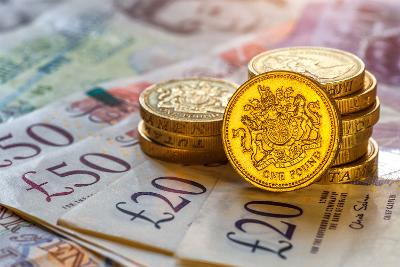 Photograph of a pile of pound coins on top of £20 and £50 notes