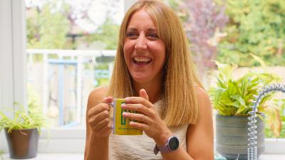 A woman holding a mug and smiling