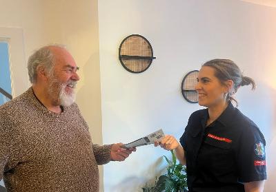 Firefighter passing a leaflet to a older man at home