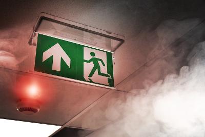 View of ceiling showing lit fire alarm, fire exit sign and visible smoke