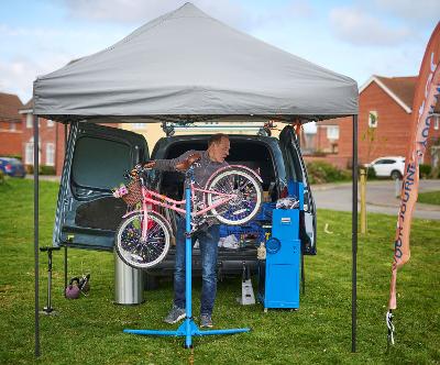 Doctor Bike repairs a bike in a small tent