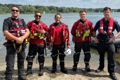 Three men standing near water in wetsuits and other protective clothing