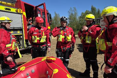People in uniforms near a fire engine taking part in water training